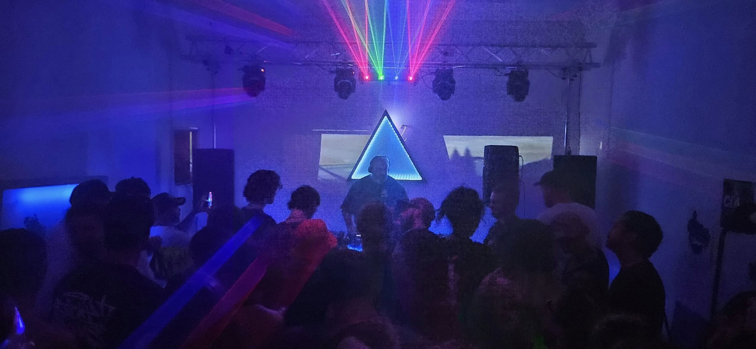 Underground DJ performing at a high energy event on the Sunshine Coast with crowd dancing and festival atmosphere